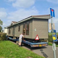 man fixing static caravan on a flatbed trailer