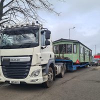 White truck with a green static caravan mounted on the flatbed