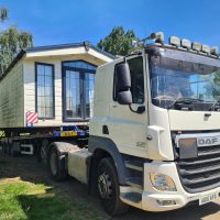 White flatbed truck transporting a mobile home