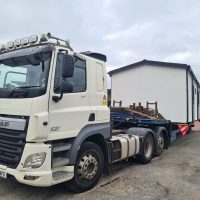 White truck hauling a static mobile home