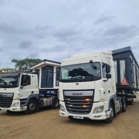 2 white flatbed lorry transporting a static caravan
