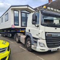 White flatbed truck with a static caravan onboard